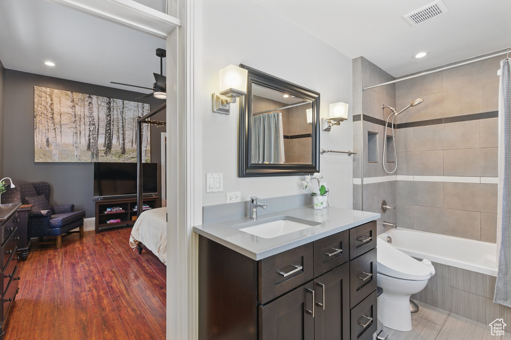 Full bathroom featuring visible vents, shower / bath combo with shower curtain, vanity, wood finished floors, and ceiling fan