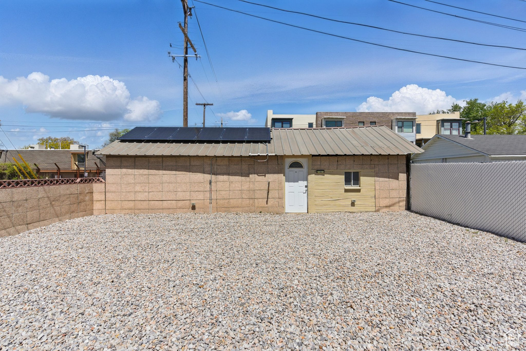 Exterior space featuring a fenced backyard, roof mounted solar panels, and metal roof