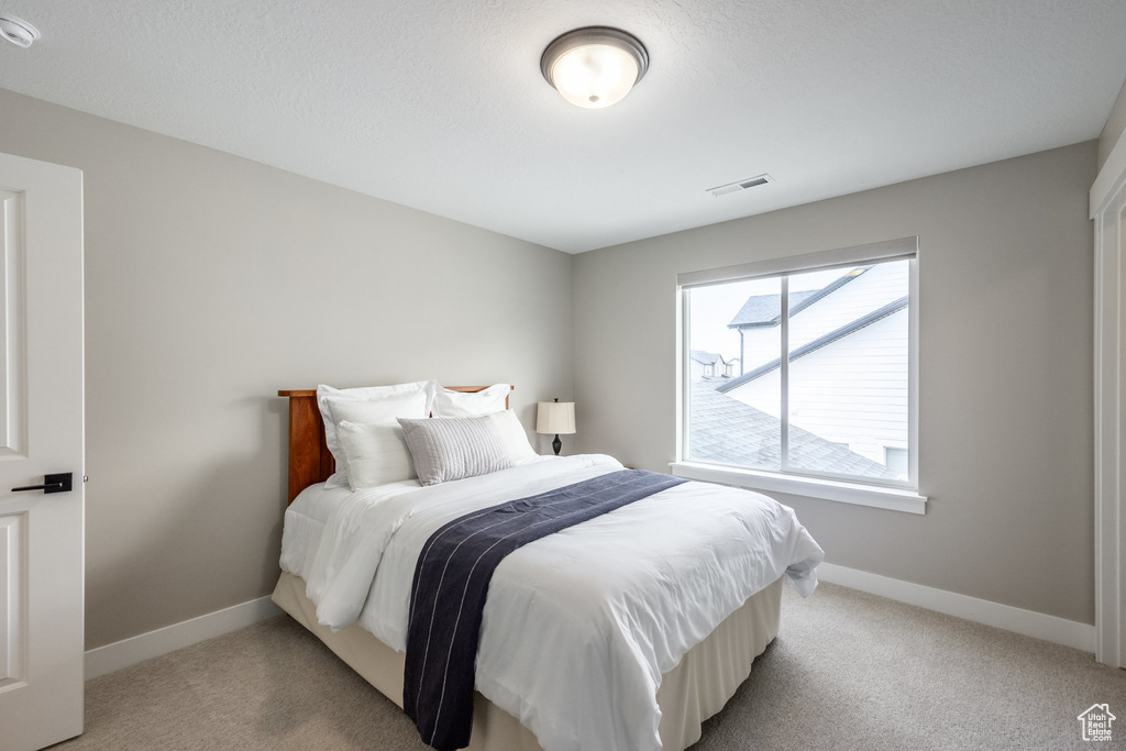 Bedroom with baseboards, light carpet, and visible vents