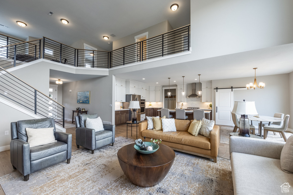 Living area featuring stairs, a barn door, recessed lighting, a high ceiling, and baseboards