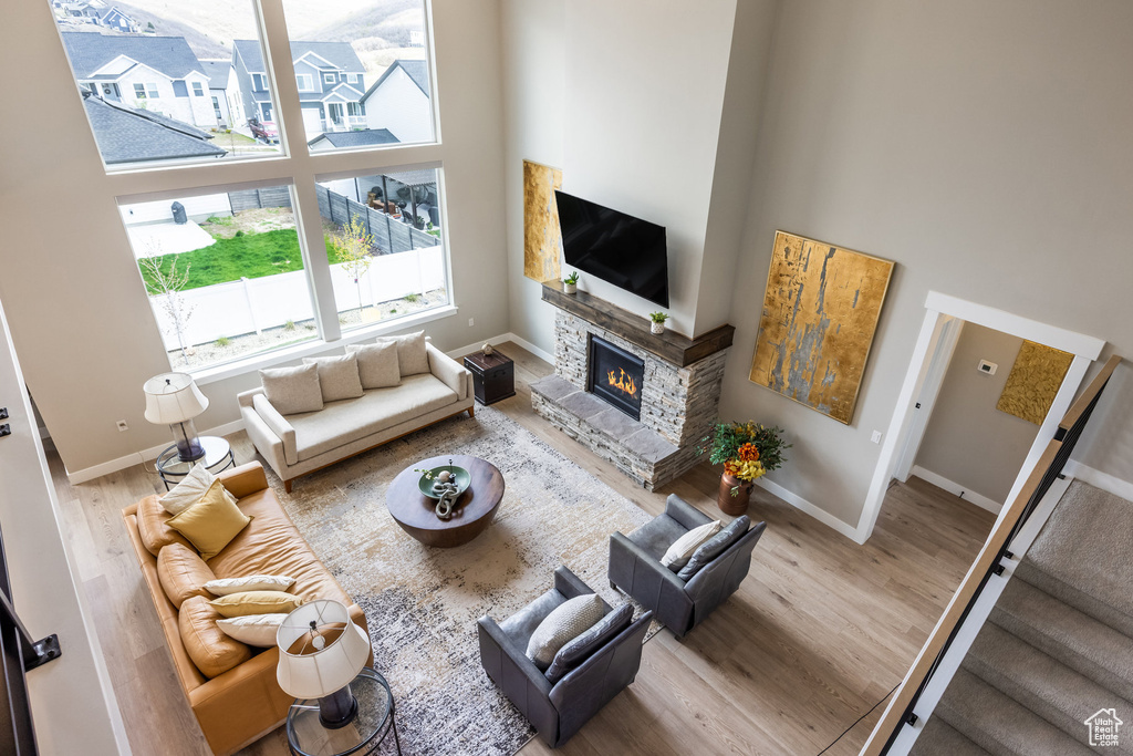 Living area featuring a high ceiling, baseboards, a stone fireplace, and wood finished floors