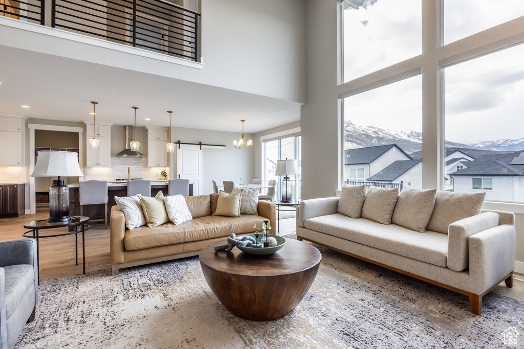 Living room with a towering ceiling, a barn door, light wood-type flooring, and a mountain view