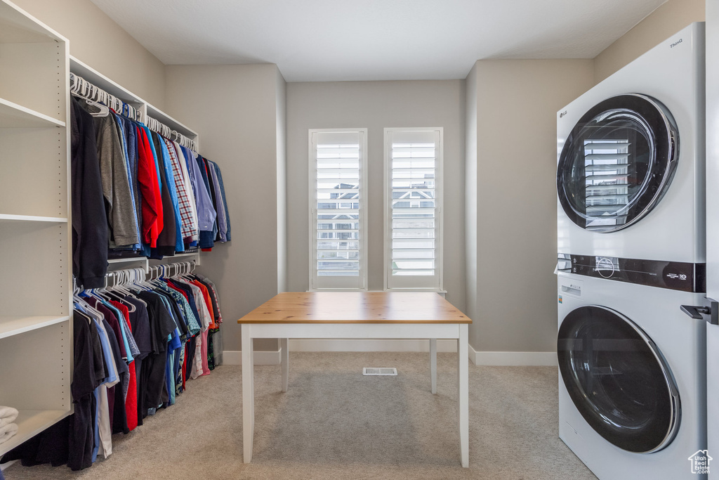 Washroom with baseboards, laundry area, stacked washer / dryer, and carpet