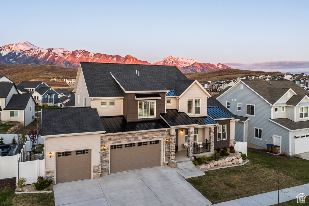 View of front of home featuring covered porch, fence, a mountain view, concrete driveway, and a standing seam roof