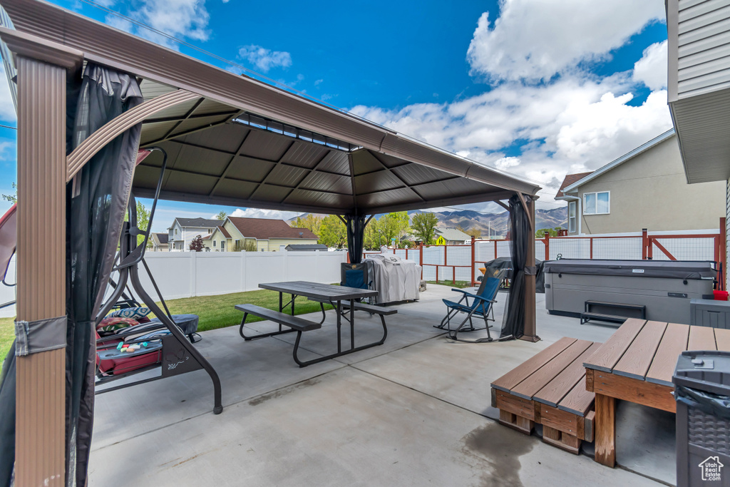 View of patio / terrace with a fenced backyard, outdoor dining space, a gazebo, and a hot tub