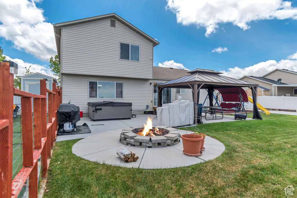 Rear view of property featuring a patio area, a hot tub, a gazebo, a yard, and a fire pit