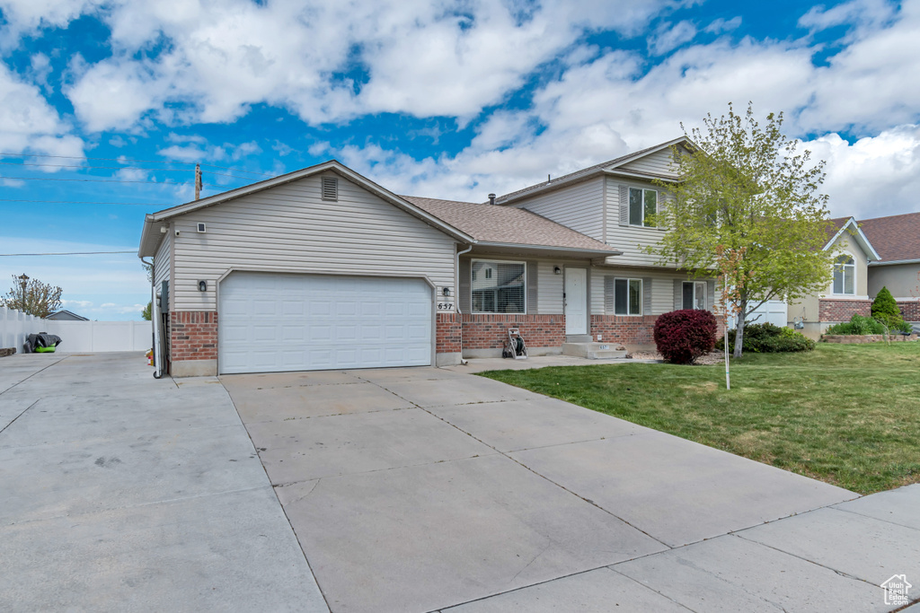 View of front of house featuring brick siding, a front lawn, an attached garage, and concrete driveway