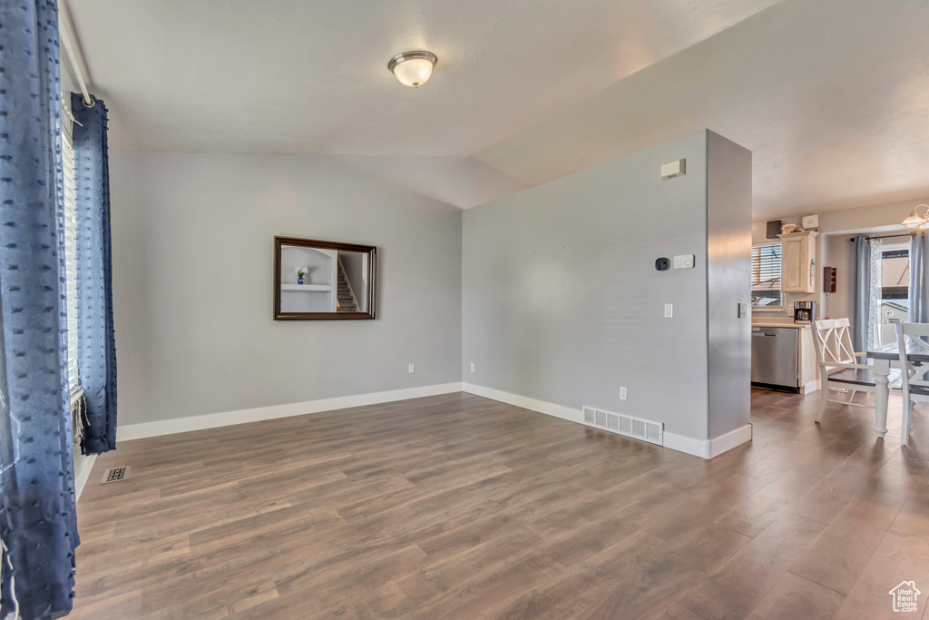 Spare room with visible vents, dark wood-style flooring, lofted ceiling, and baseboards