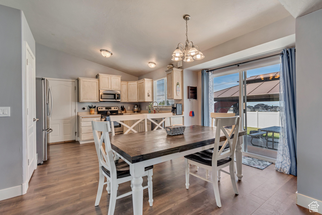 Dining space with baseboards, a chandelier, wood finished floors, and lofted ceiling