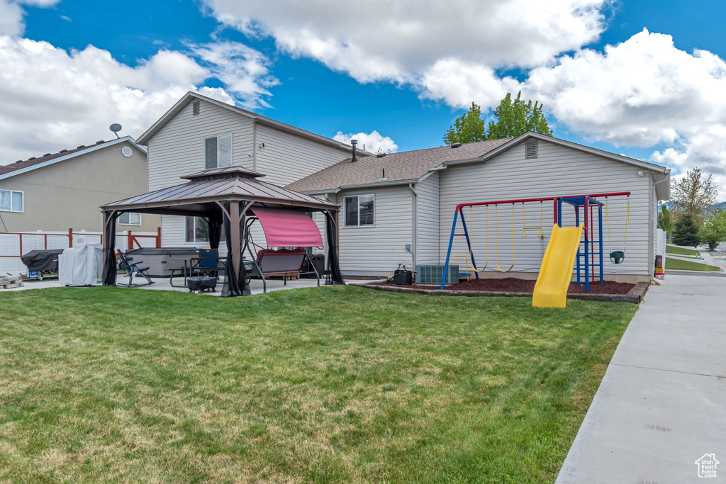 Back of house featuring a playground, a patio, a gazebo, and a lawn