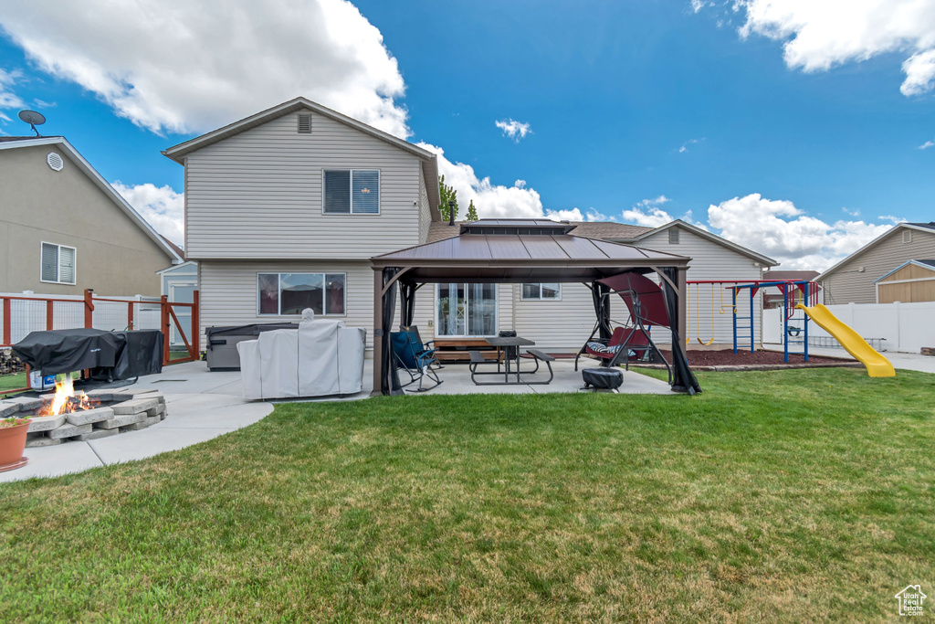Back of house with fence, a gazebo, an outdoor fire pit, a patio, and a yard