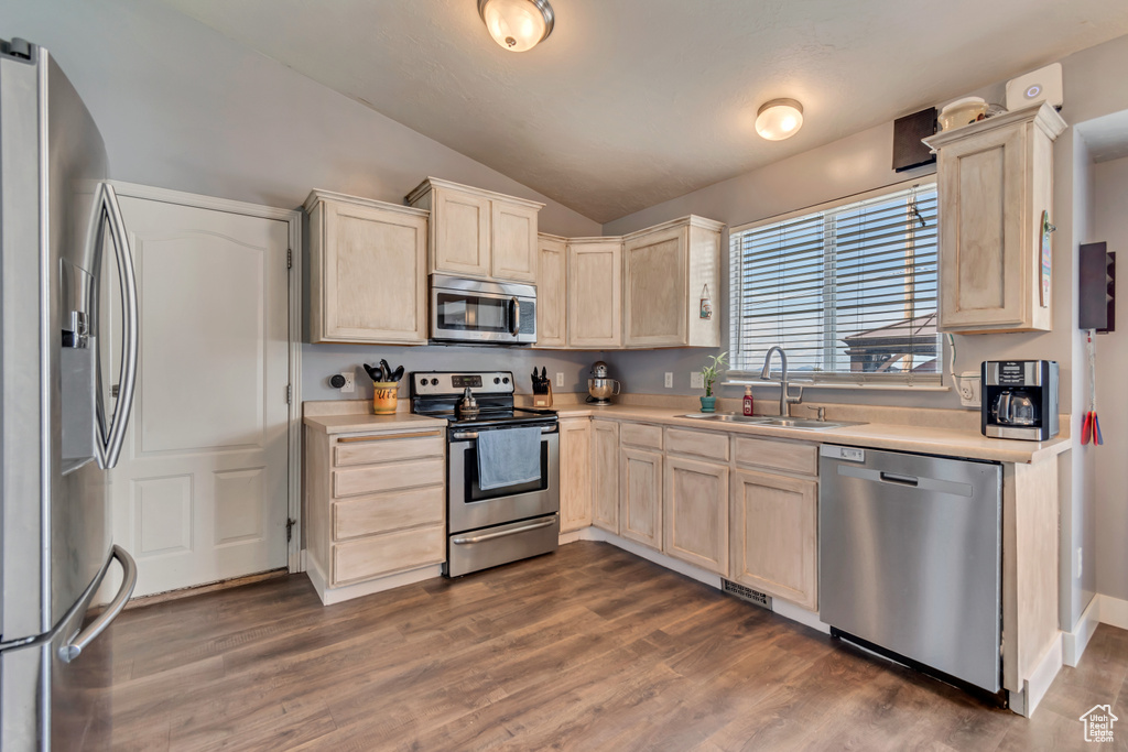 Kitchen with a sink, light countertops, lofted ceiling, light brown cabinets, and stainless steel appliances