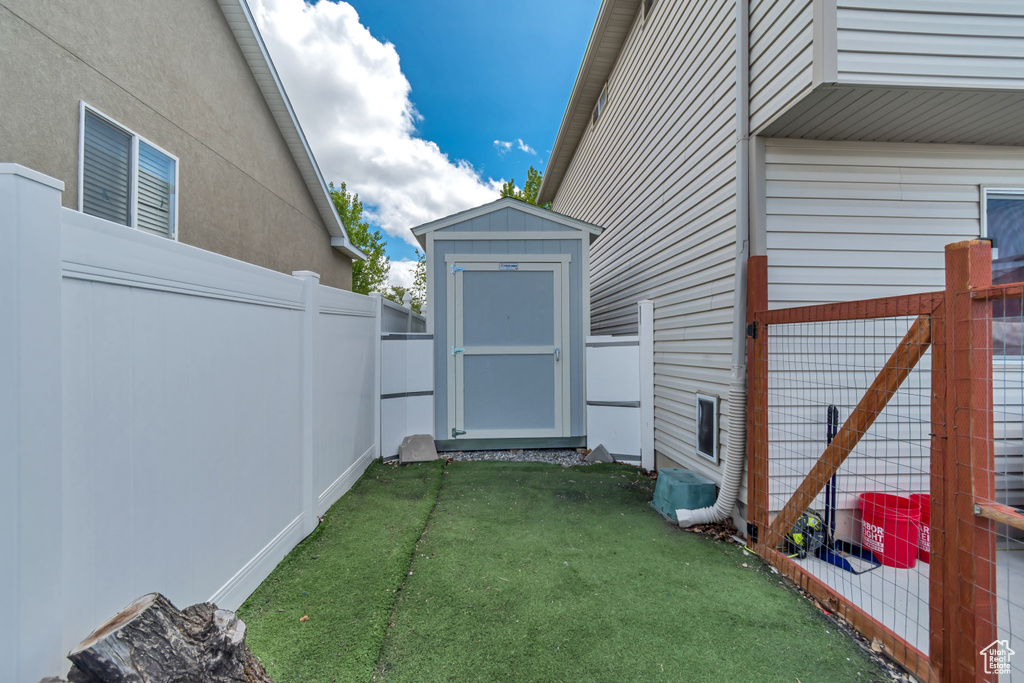 View of yard with a storage shed, fence, and an outbuilding