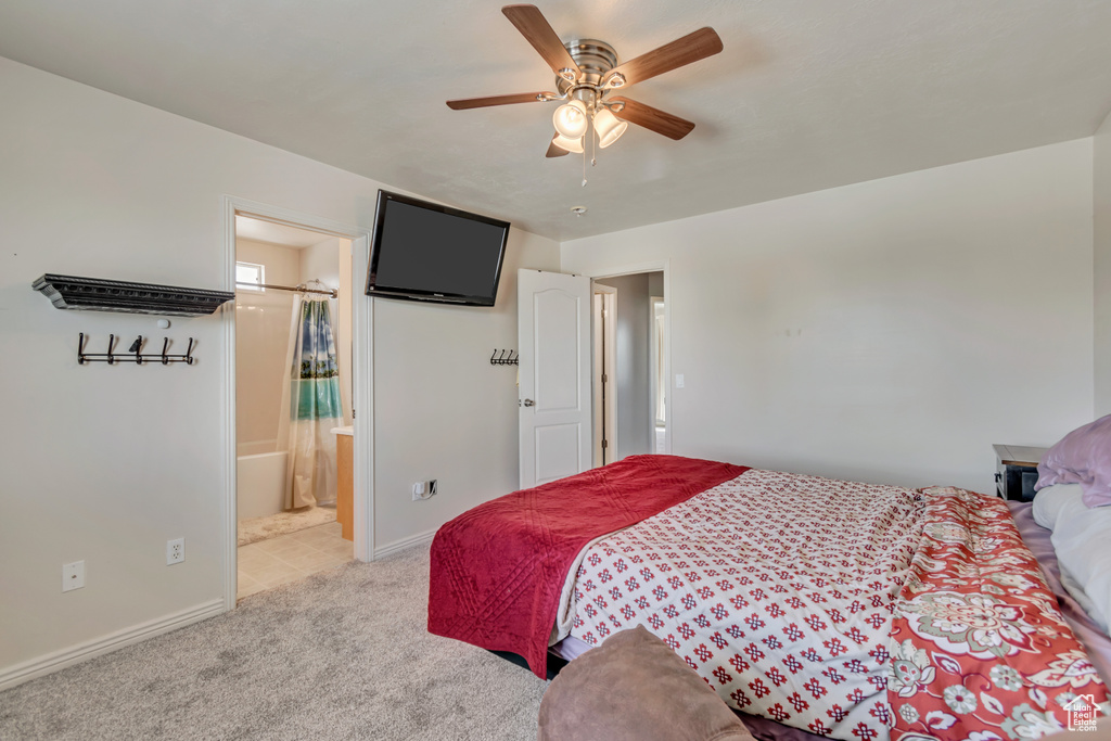 Bedroom with baseboards, ensuite bathroom, light carpet, and a ceiling fan