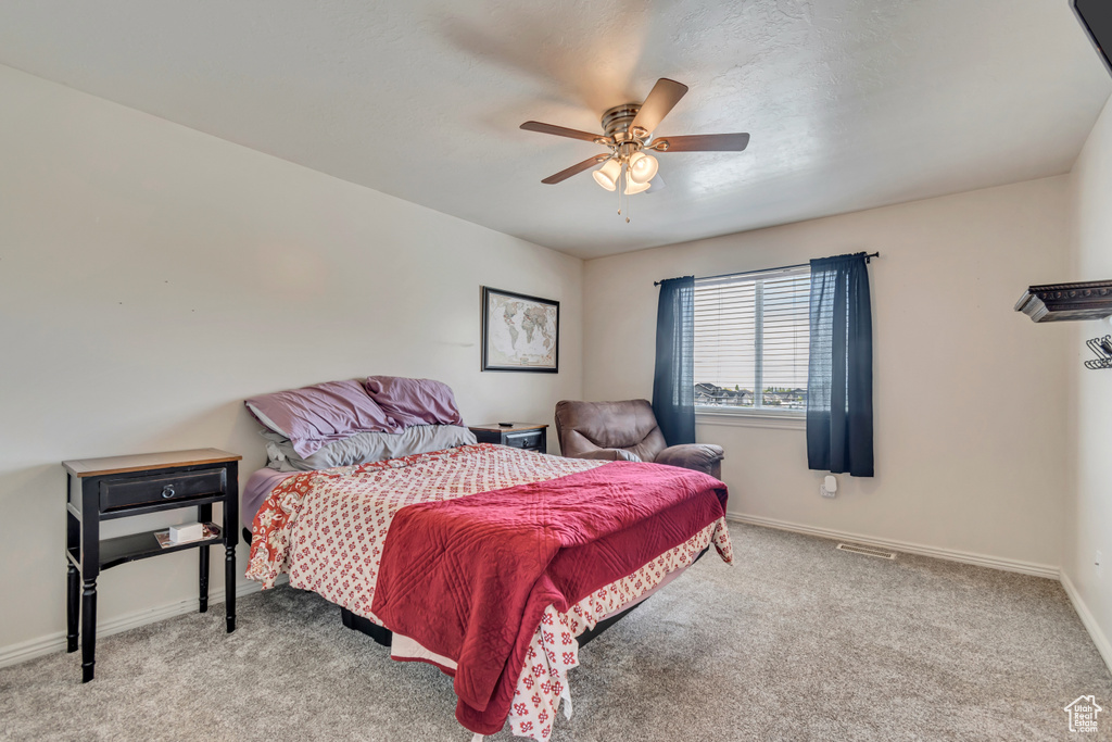 Carpeted bedroom featuring baseboards, a ceiling fan, and visible vents