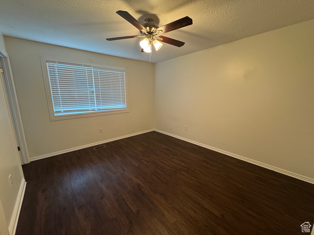 Spare room with baseboards, a ceiling fan, a textured ceiling, and dark wood-type flooring