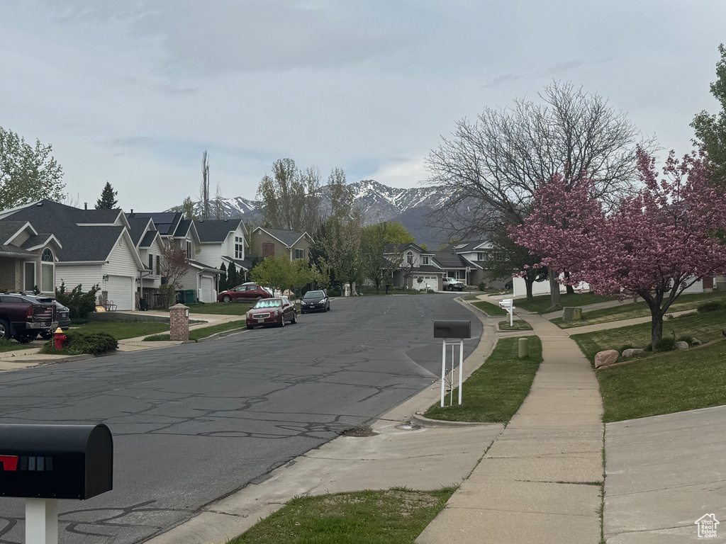 View of street with a residential view, sidewalks, a mountain view, and curbs