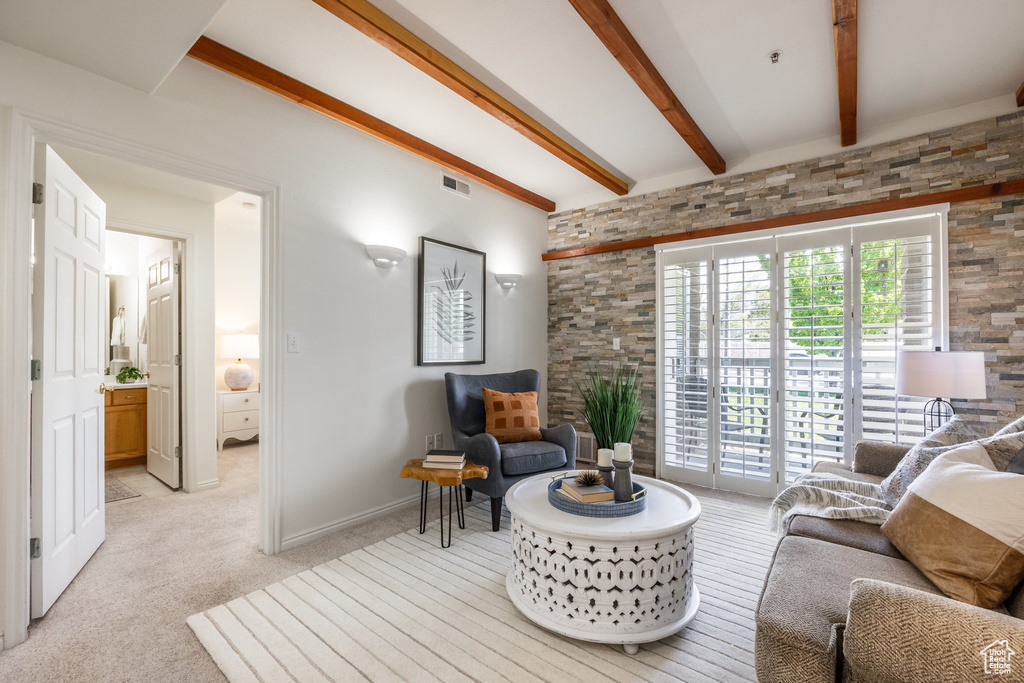 Living room featuring visible vents, light carpet, and beamed ceiling