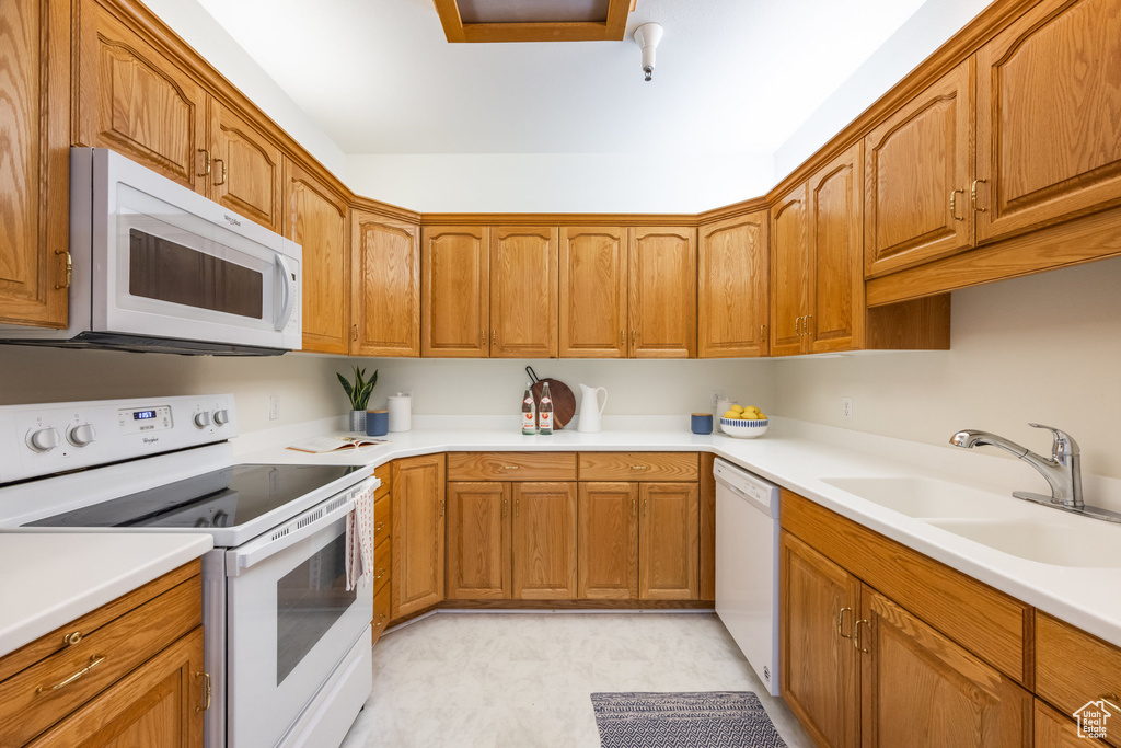 Kitchen with a sink, brown cabinets, and white appliances