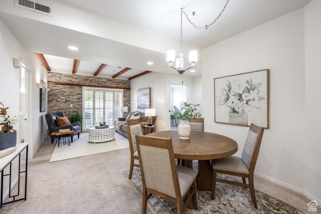Carpeted dining area featuring visible vents, beam ceiling, baseboards, recessed lighting, and a chandelier