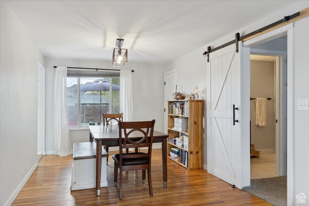 Dining room with baseboards, a barn door, and wood finished floors