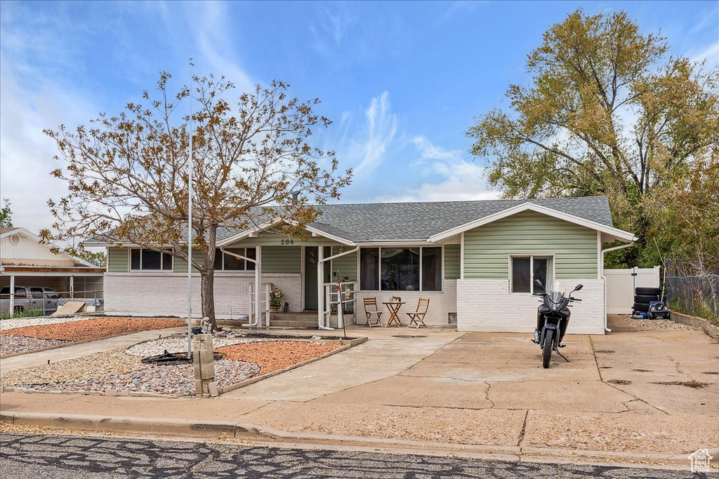 Ranch-style home with brick siding, roof with shingles, fence, and a porch