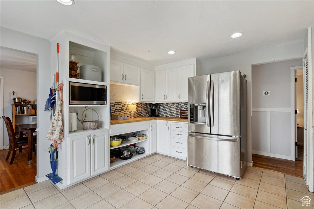 Kitchen featuring light countertops, white cabinetry, open shelves, and appliances with stainless steel finishes