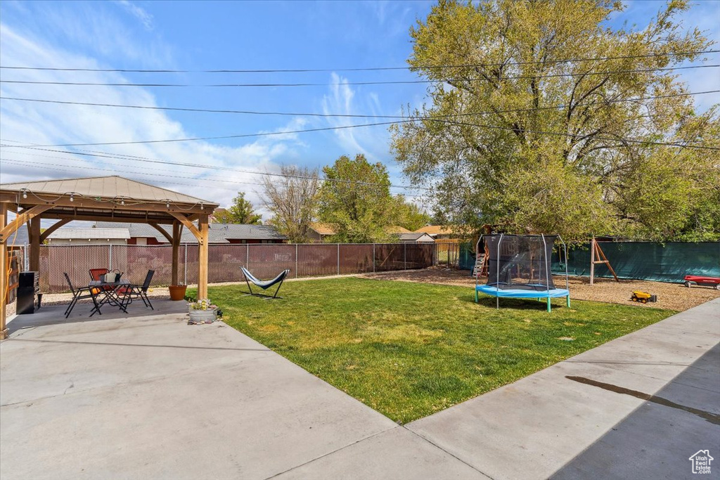 View of yard with a trampoline, a patio area, a gazebo, a fenced backyard, and a playground
