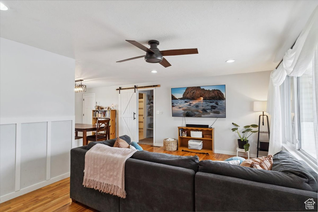 Living area with light wood-style floors, ceiling fan, recessed lighting, and a barn door