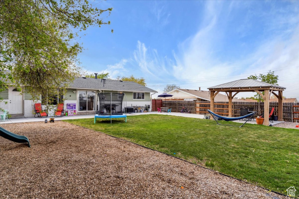 View of yard with a trampoline, a gazebo, a fenced backyard, a playground, and a patio