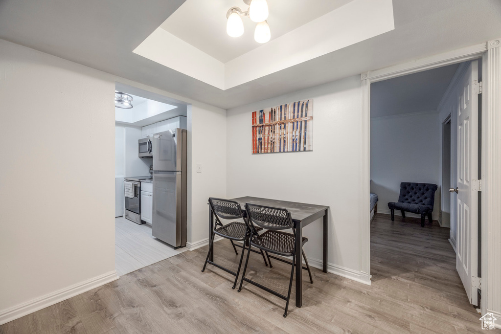 Dining space featuring light wood-style floors, baseboards, and a tray ceiling