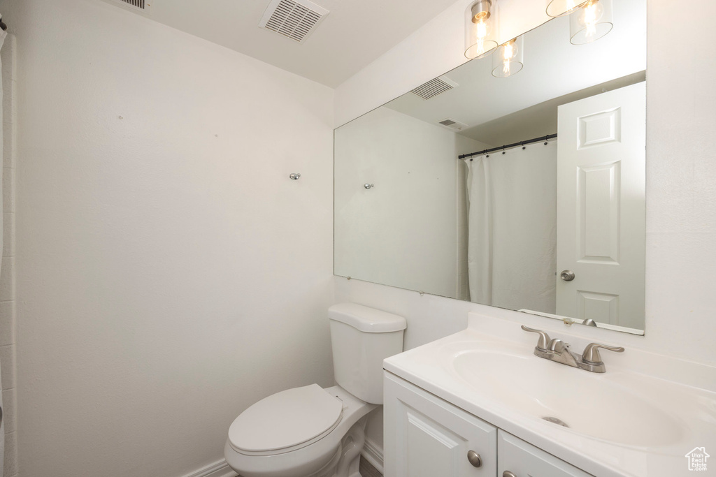 Full bath featuring visible vents, baseboards, toilet, and vanity
