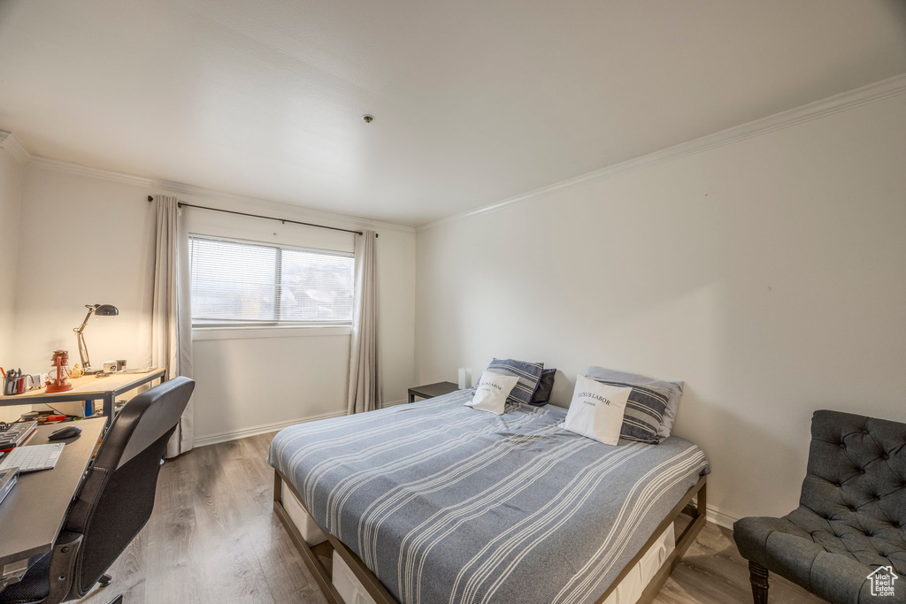 Bedroom featuring crown molding, baseboards, and wood finished floors