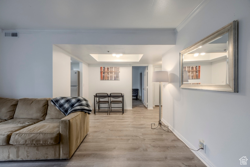 Living room featuring visible vents, crown molding, baseboards, light wood-style flooring, and a skylight