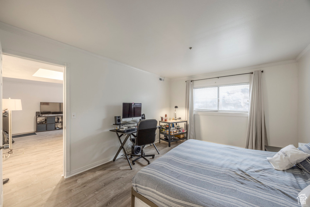 Bedroom with baseboards, visible vents, ornamental molding, and light wood-type flooring