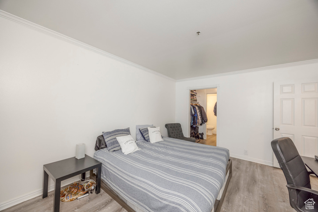 Bedroom featuring baseboards, ornamental molding, and light wood-style floors
