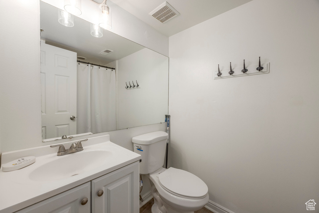 Full bathroom with toilet, baseboards, visible vents, and vanity