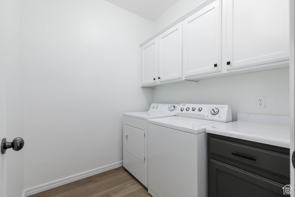 Laundry room with baseboards, washer and clothes dryer, cabinet space, and light wood finished floors