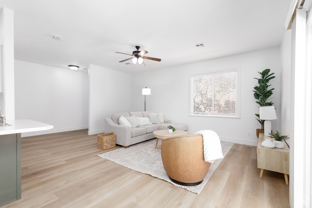 Living room with baseboards, a ceiling fan, light wood-style flooring, and visible vents
