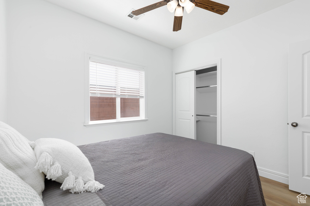 Bedroom featuring ceiling fan, visible vents, wood finished floors, baseboards, and a closet