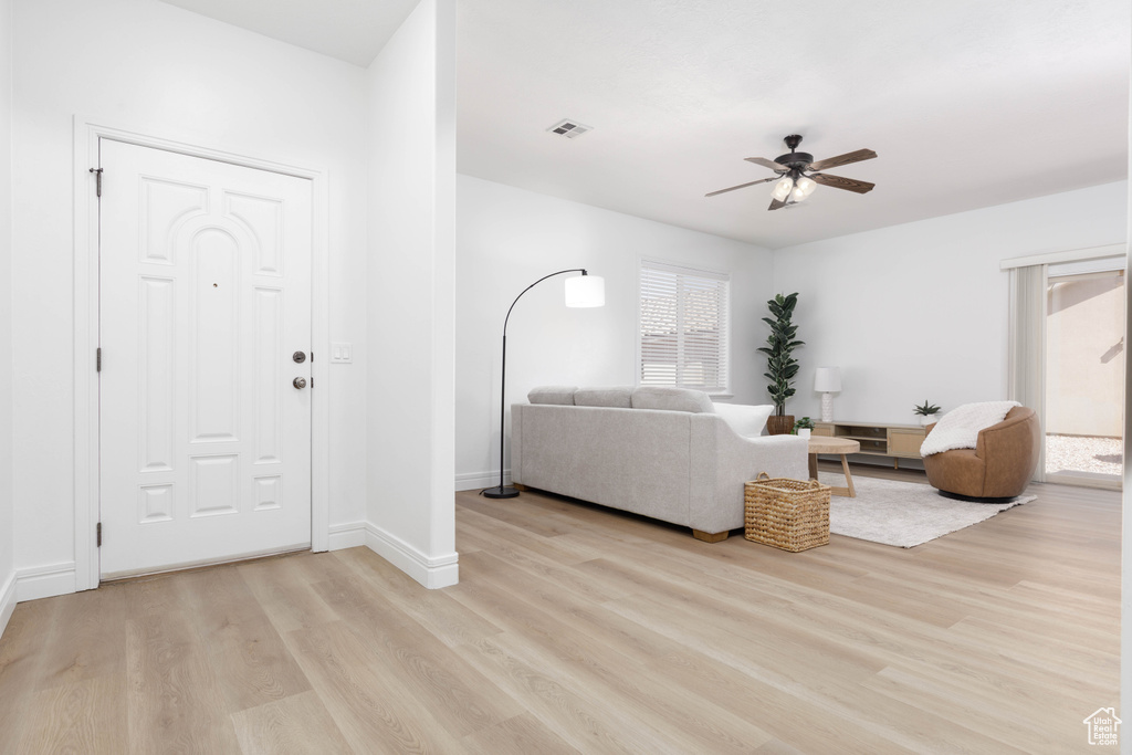 Living room with light wood-style floors, baseboards, a ceiling fan, and visible vents