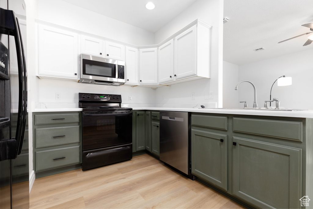 Kitchen featuring white cabinets, light wood-style flooring, a sink, and black appliances
