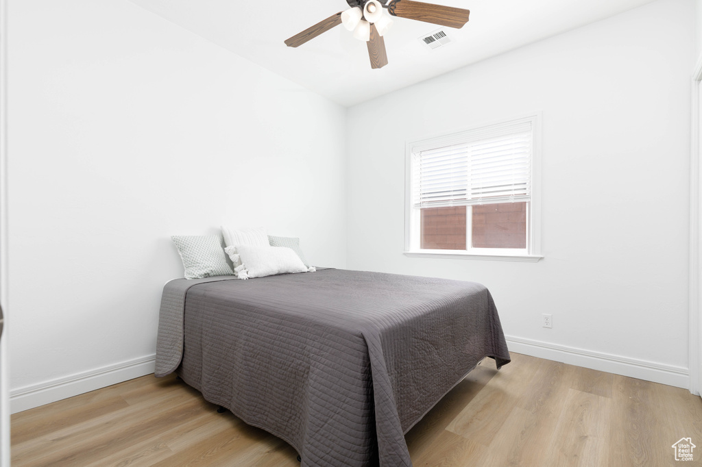 Bedroom featuring baseboards, ceiling fan, light wood-type flooring, and visible vents