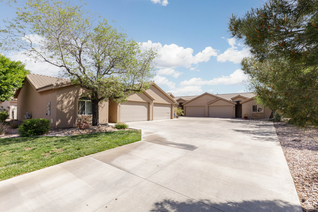 Single story home with a garage, stucco siding, a tiled roof, and concrete driveway