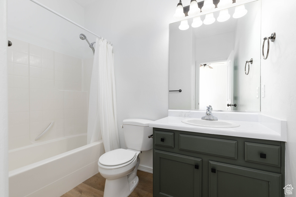 Full bathroom with vanity, toilet, wood finished floors, and shower / tub combo