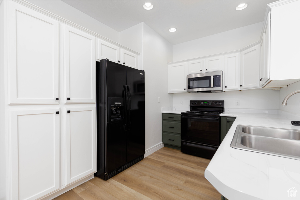 Kitchen featuring a sink, light countertops, black appliances, and light wood-type flooring