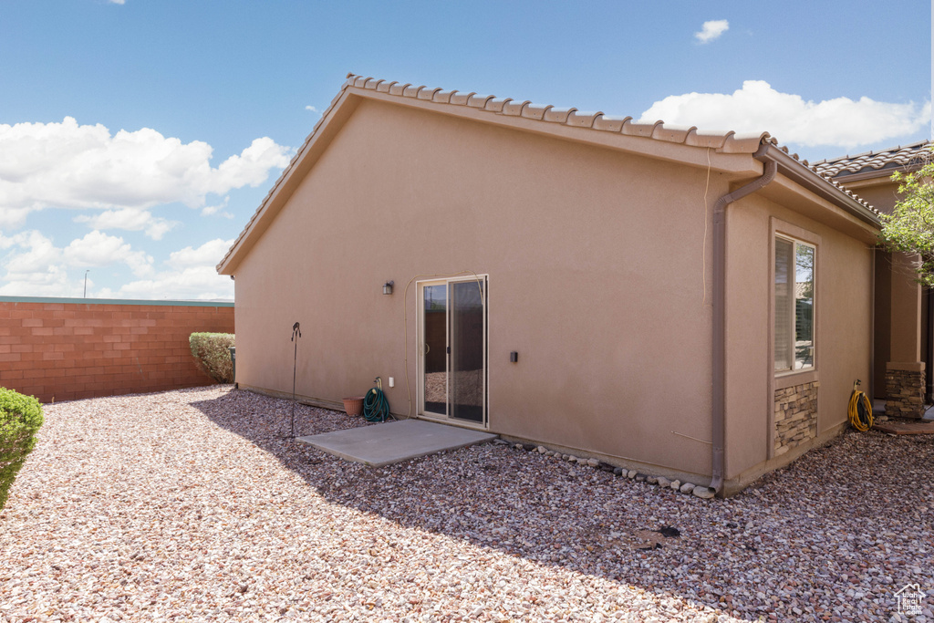 Back of property featuring fence, stucco siding, and a tiled roof