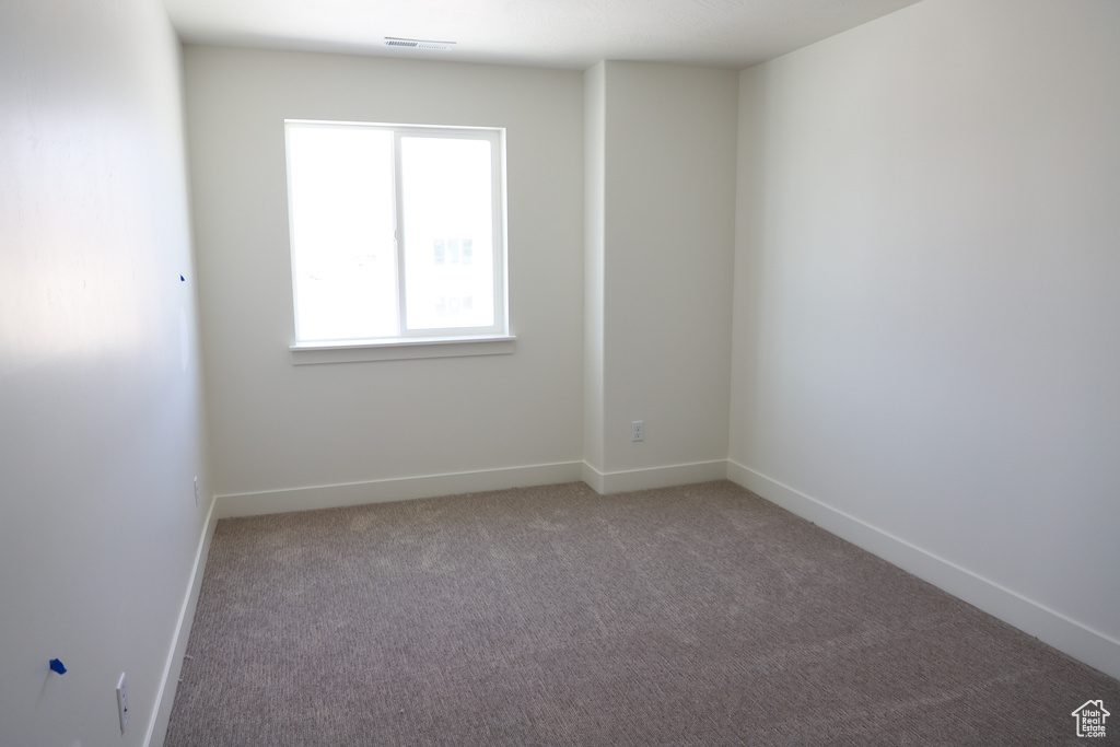 Carpeted spare room with visible vents and baseboards