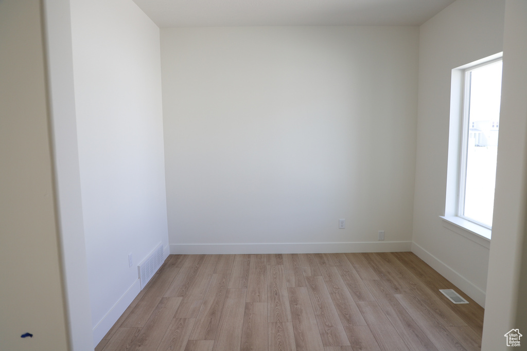 Empty room featuring visible vents, light wood-style flooring, and baseboards