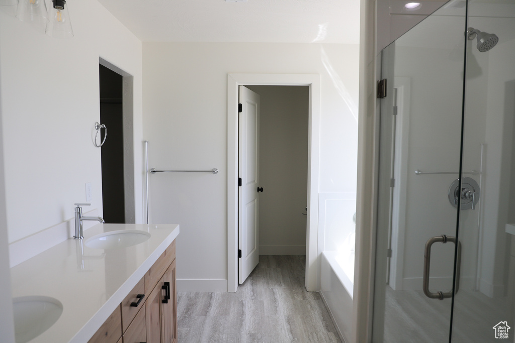 Full bath with wood finished floors, a sink, a stall shower, and double vanity